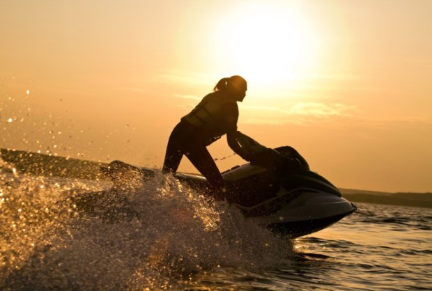 beautiful girl riding her jet skis in the sea at sunset . spray